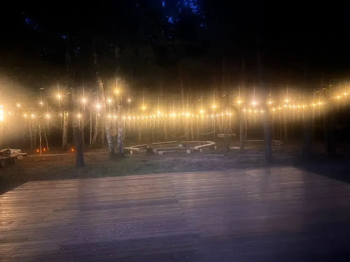 Drewniana scena pod girlandami żarówek nocą