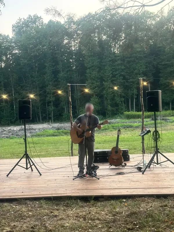 Muzyk z gitarą na drewnianej scenie pod girlandami